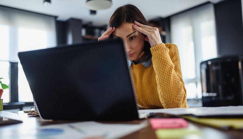 Junge Frau, sitzt verzweifelt vor dem Laptop.