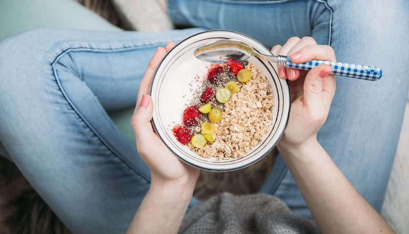 Müsli-Bowl auf dem Schoß einer Frau.