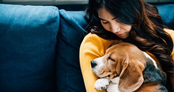 Frau, hält einen Hund an ihre Brust.