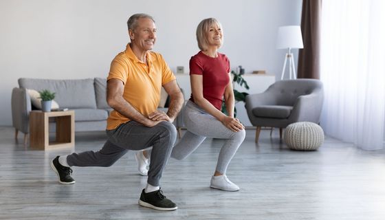 Älteres Paar macht Gymnastik im Wohnzimmer.