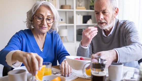 Ein älteres Paar frühstückt Himbeeren und andere Früchten.