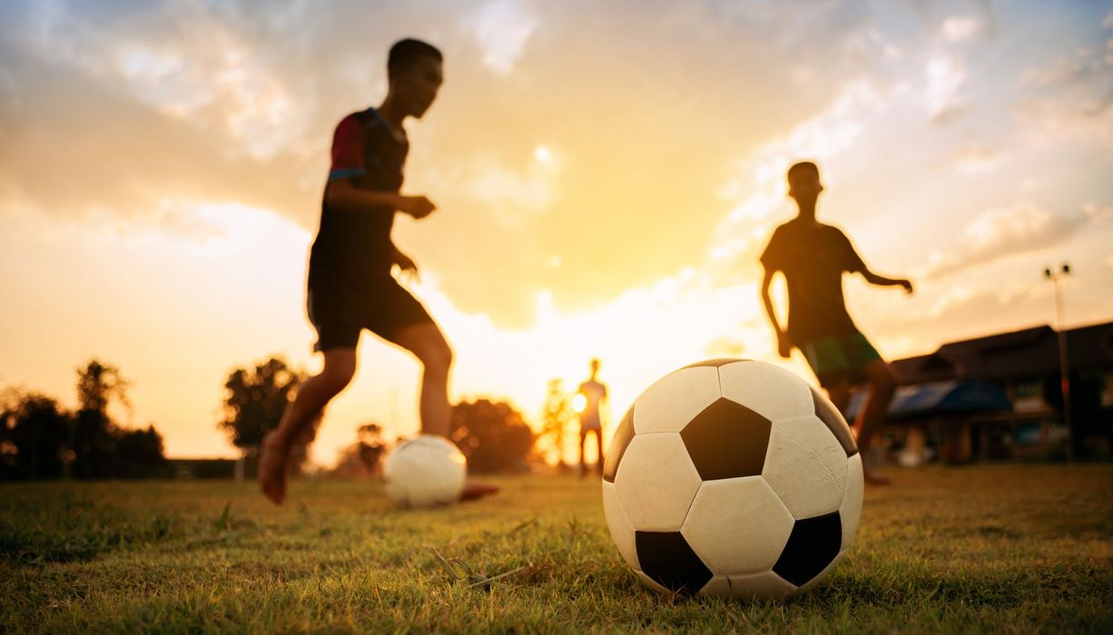 Zwei Jungen spielen Fußball auf einem Rasen.