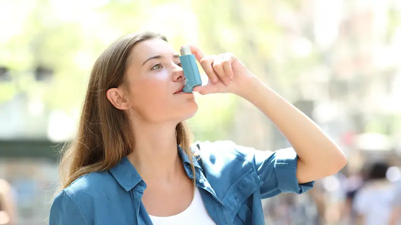 Frau benutzt Asthmaspray.