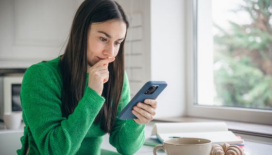 Junge Frau, schaut nachdenklich ins Smartphone.