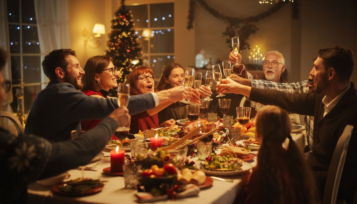 Familie, stößt beim Weihnachtsessen mit Sekt an.