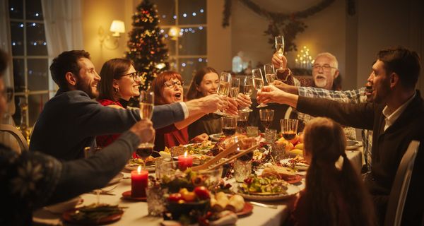 Familie, stößt beim Weihnachtsessen mit Sekt an.