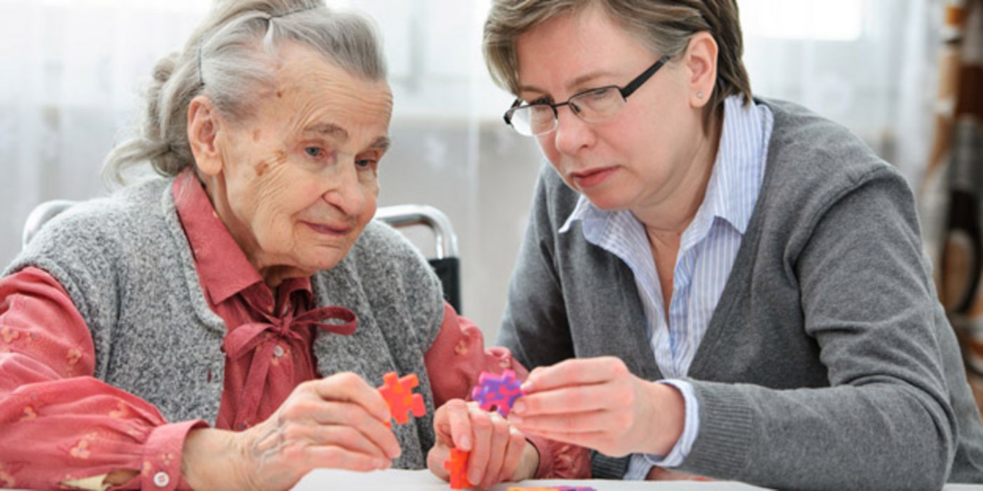 Alte Frau (ca. 80) beim Puzzeln mit Frau in den 40ern