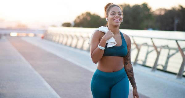 Junge Frau im sportlichen Outfit, läuft einen Weg entlang.