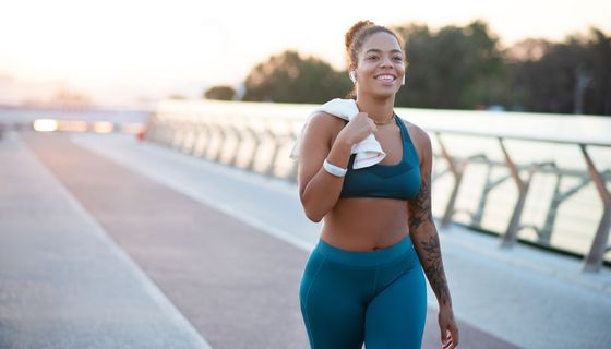 Junge Frau im sportlichen Outfit, läuft einen Weg entlang.