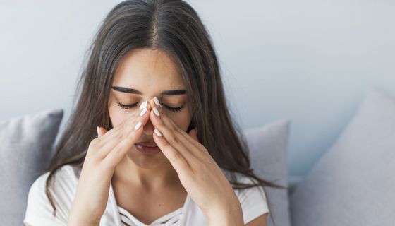 Erkältete Frau hält sich die Nase.