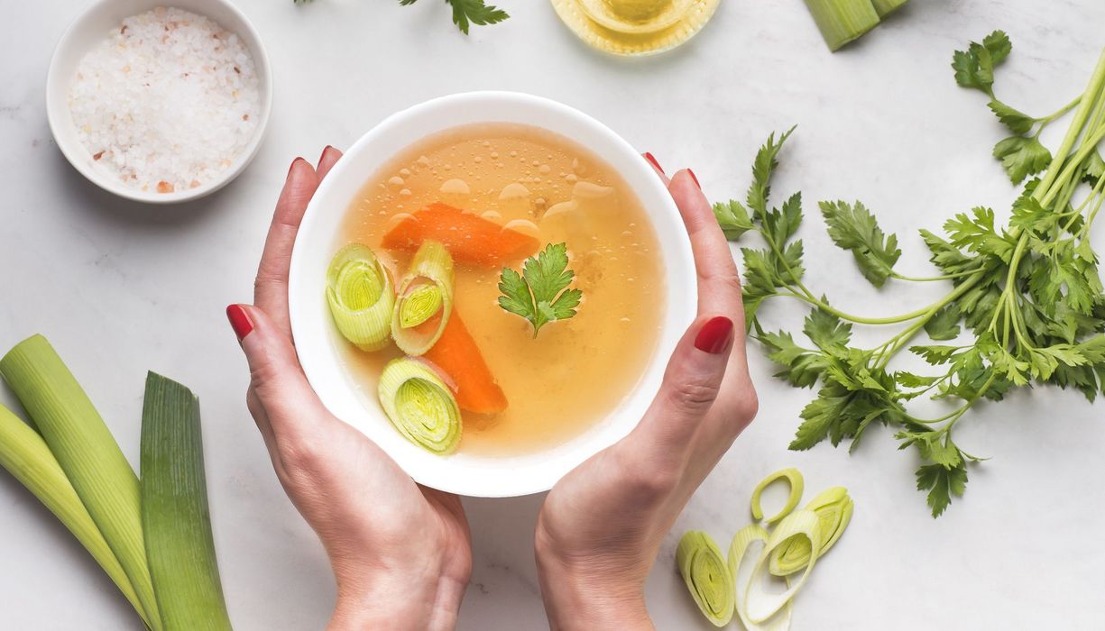 Frau, hält eine Schüssel mit Gemüsesuppe zwischen den Händen.