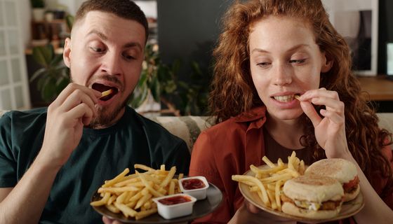 Ein Paar isst Pommes mit Burgern und Dips.