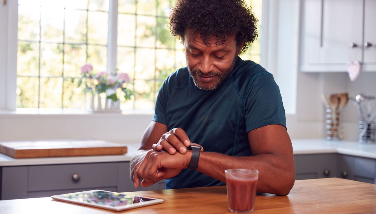 Mann, schaut auf sein Fitness-Armband.