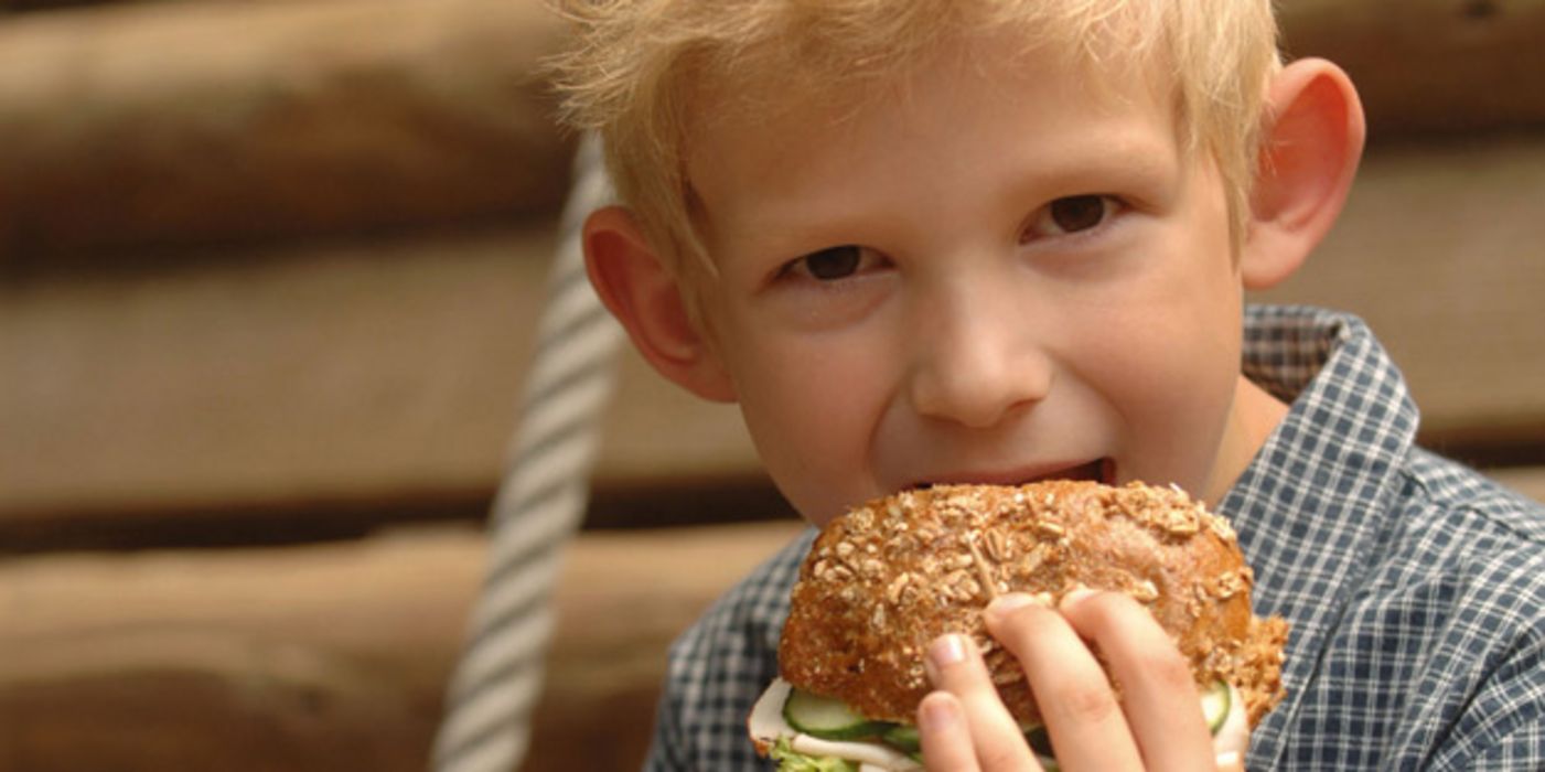 Kleiner Junge isst ein Vollkornbrötchen