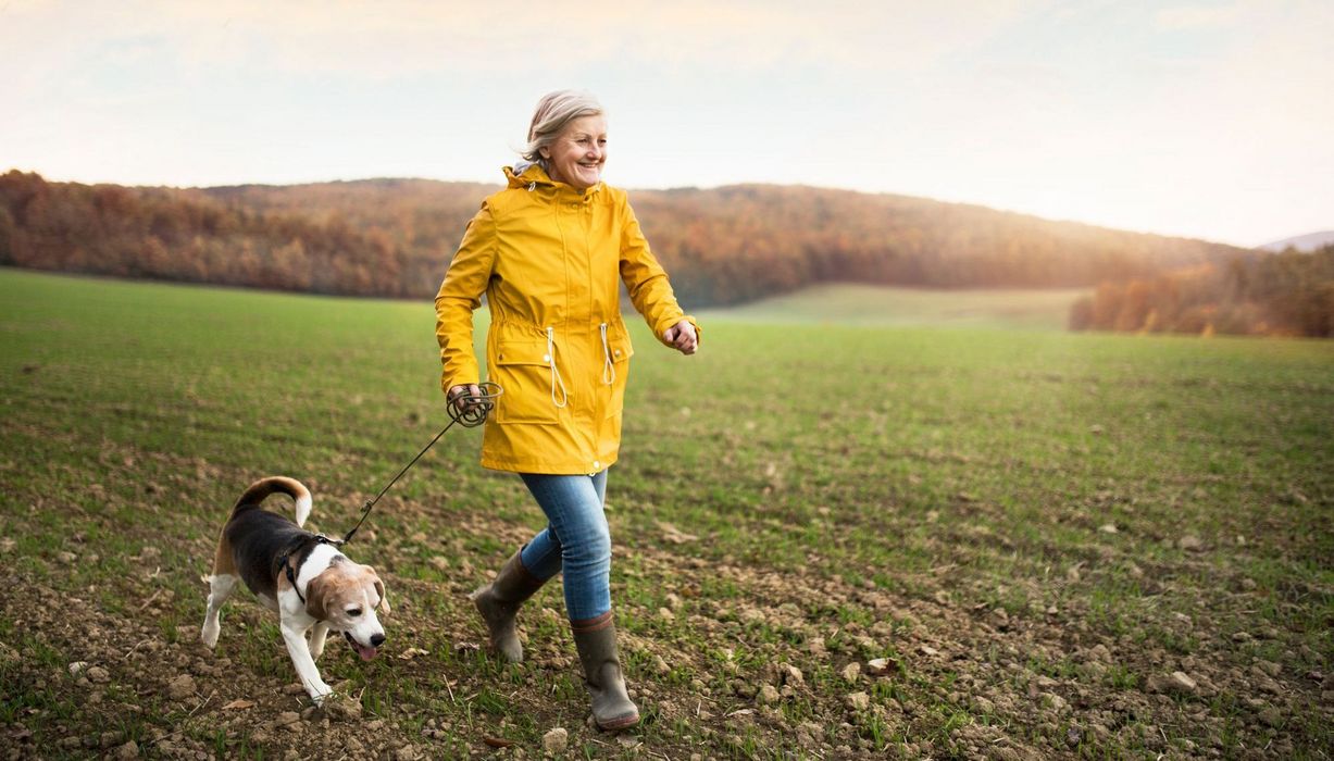 Ältere Frau, geht mit ihrem Hund spazieren.