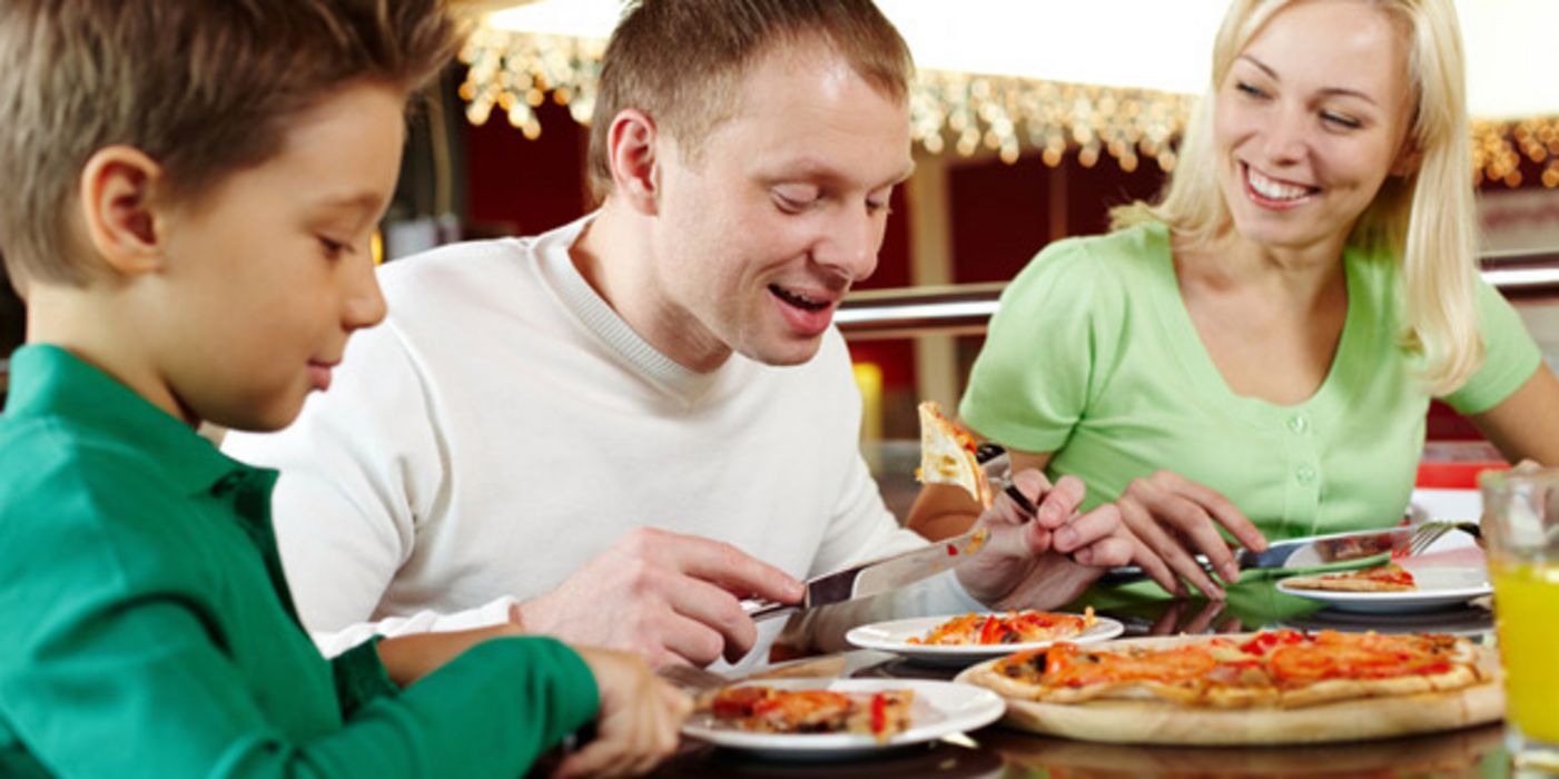 Familie isst Pizza am Tisch.