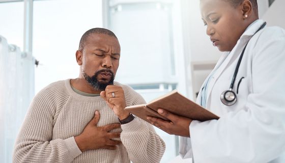 Mann hustet bei einer Ärztin