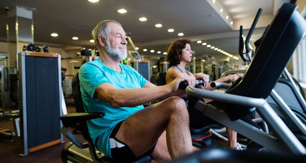 Älterer Mann, trainiert auf einem Rudergerät im Fitnessstudio.