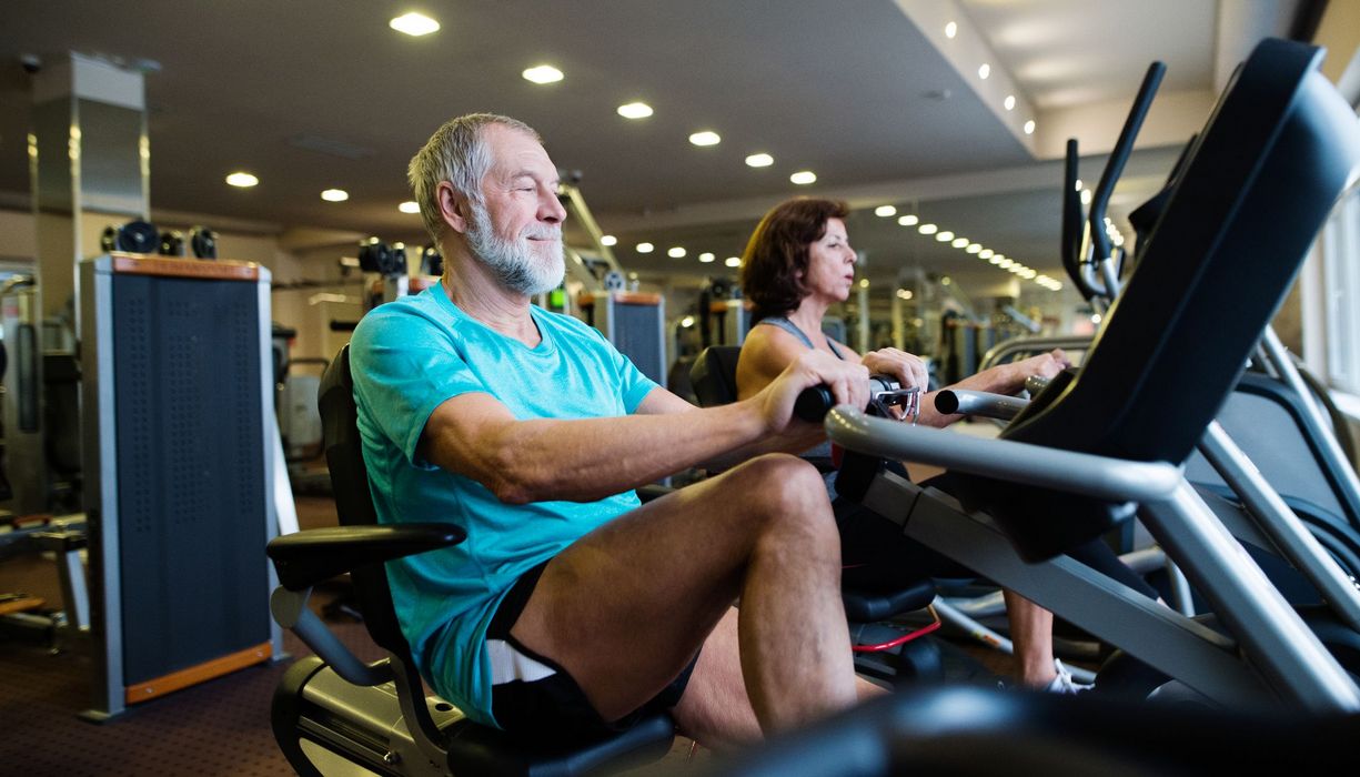 Älterer Mann, trainiert auf einem Rudergerät im Fitnessstudio.