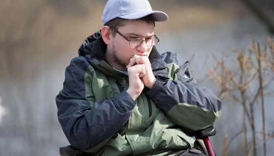 Ein junger Mann im Rollstuhl blickt traurig.