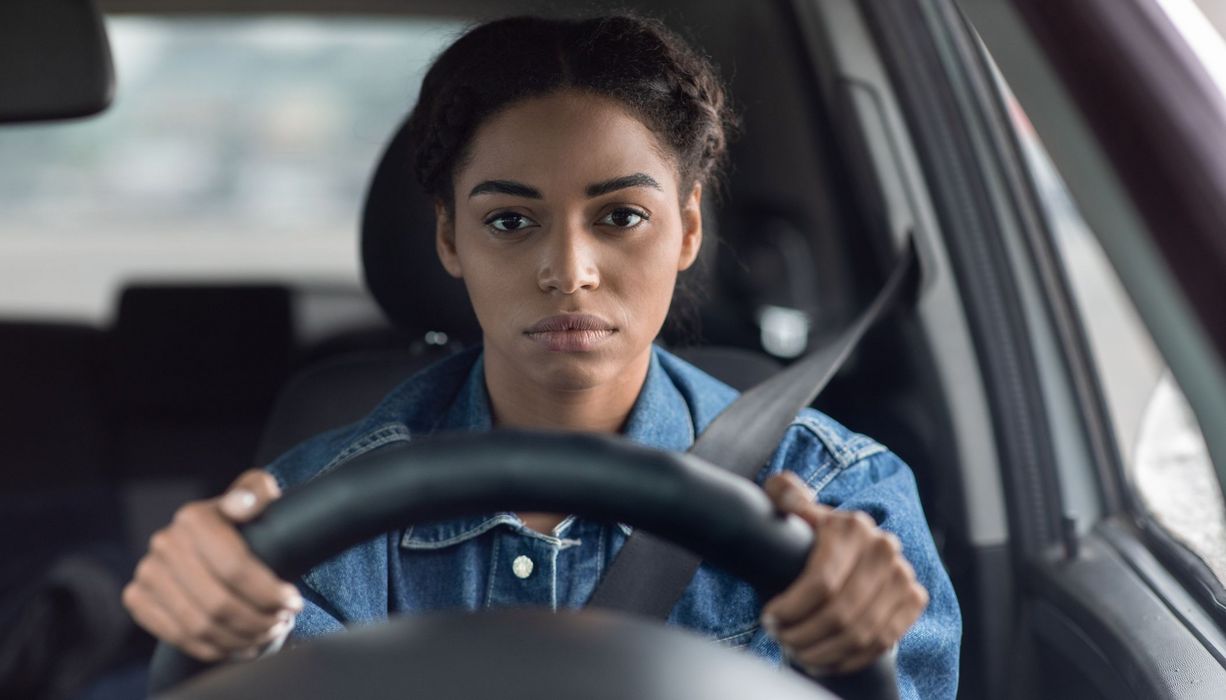 Junge Frau, sitzt hinter dem Steuer eines Autos.