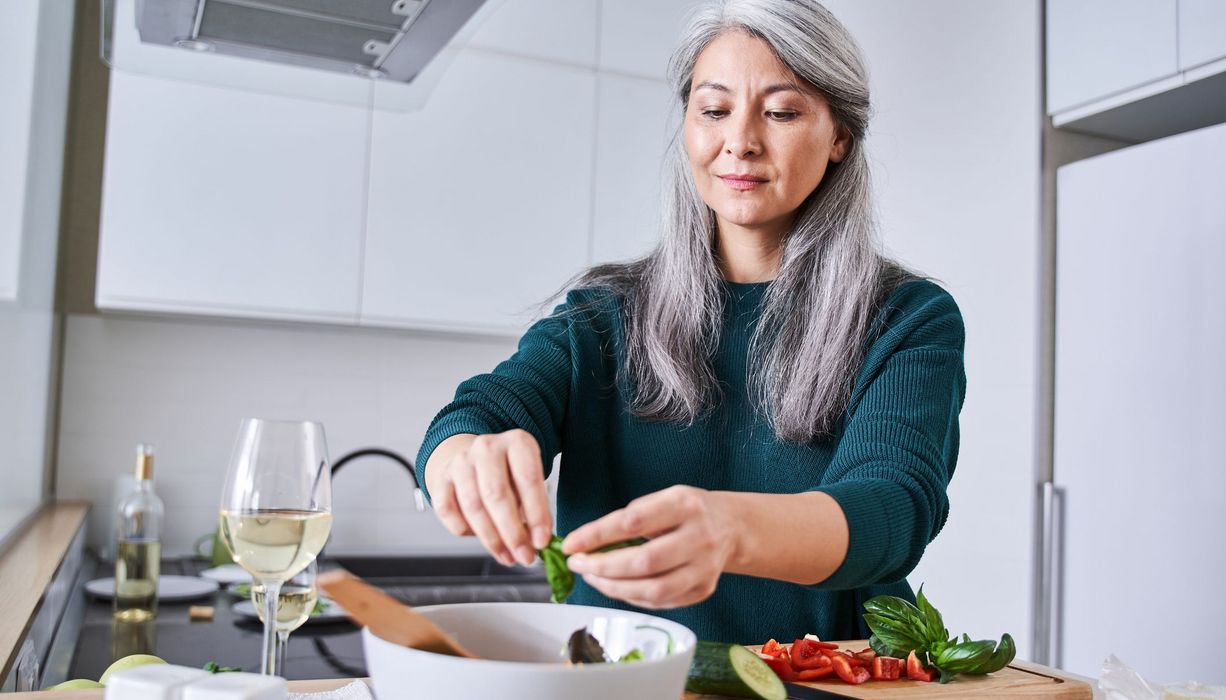 Ältere Frau, macht sich einen Salat.