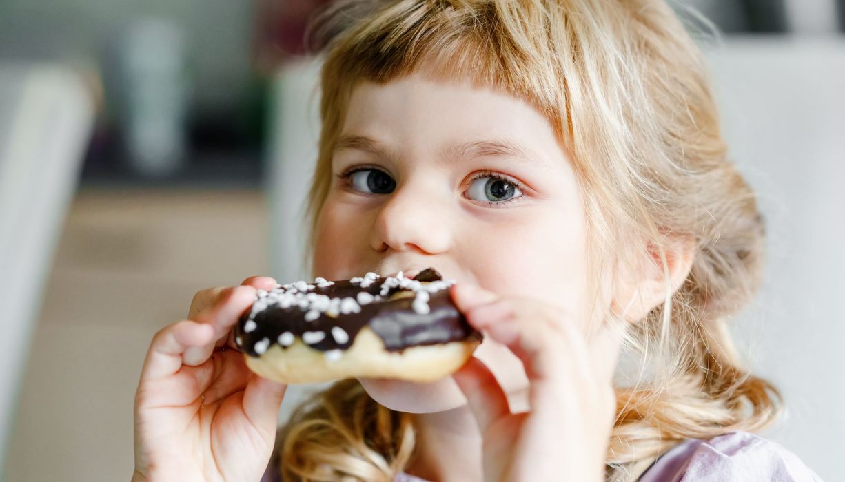 Junges Mädchen, beißt in einen Donut.