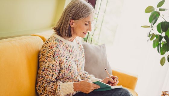 ältere Frau schreibt in ein Buch