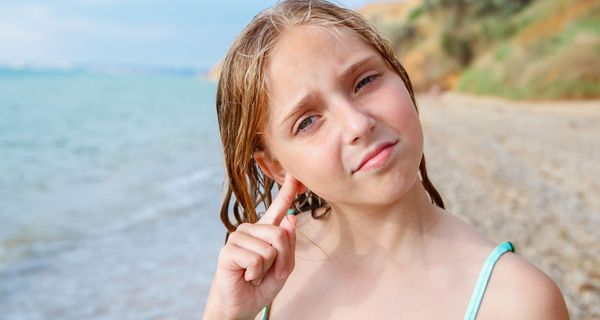 Mädchen, fasst sich ans Ohr.