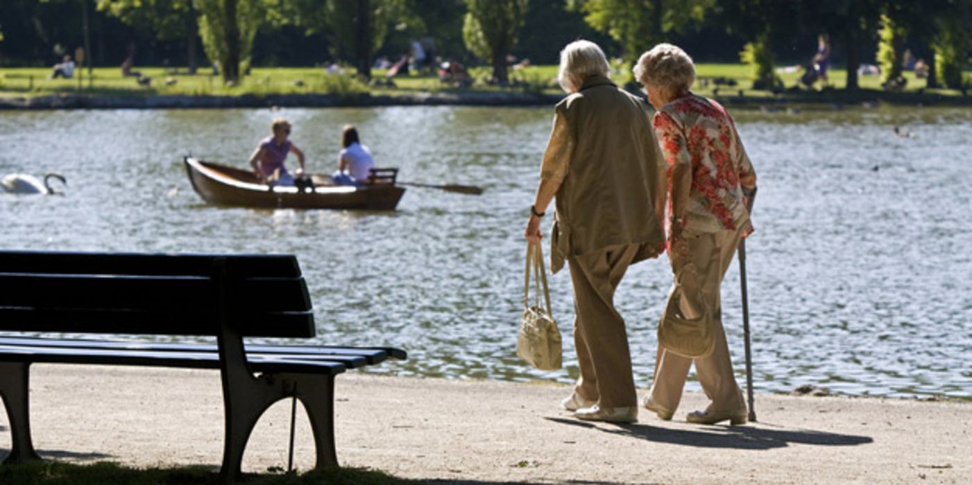 Zwei Seniorinnen gehen an einem Weiher spazieren