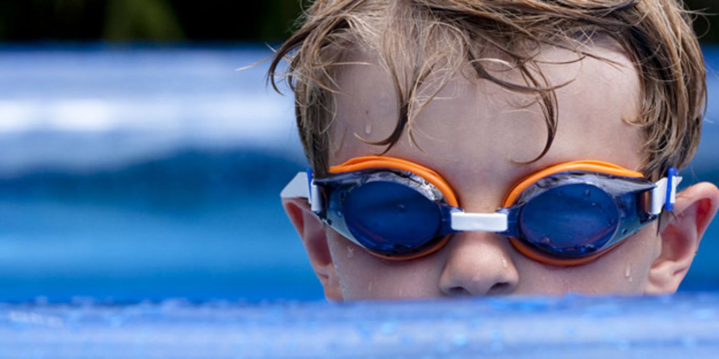 Kleiner Junge mit Schwimmbrille im Freibad