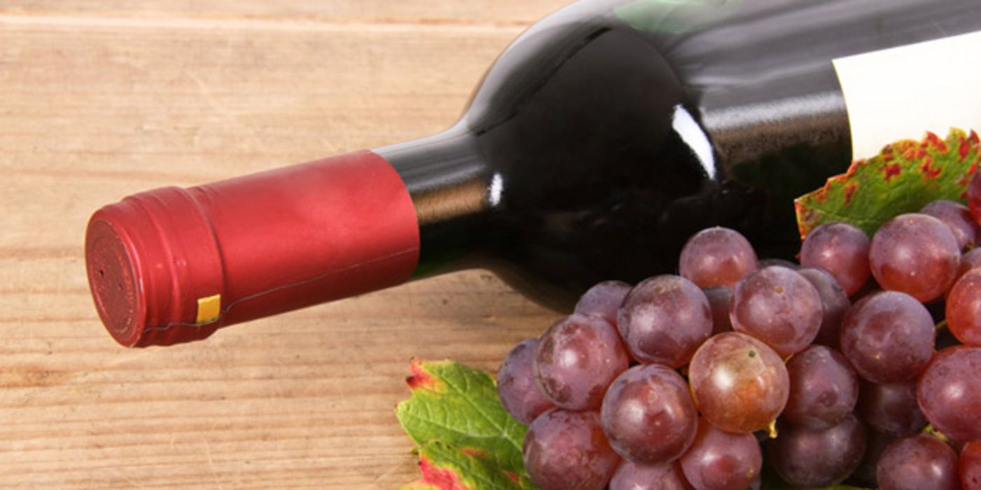 Liegende Flasche Rotwein und rote Weintrauben