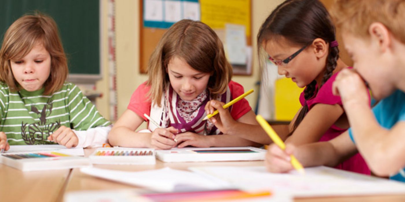 Vier Grundschüler arbeiten konzentriert an einem Tisch