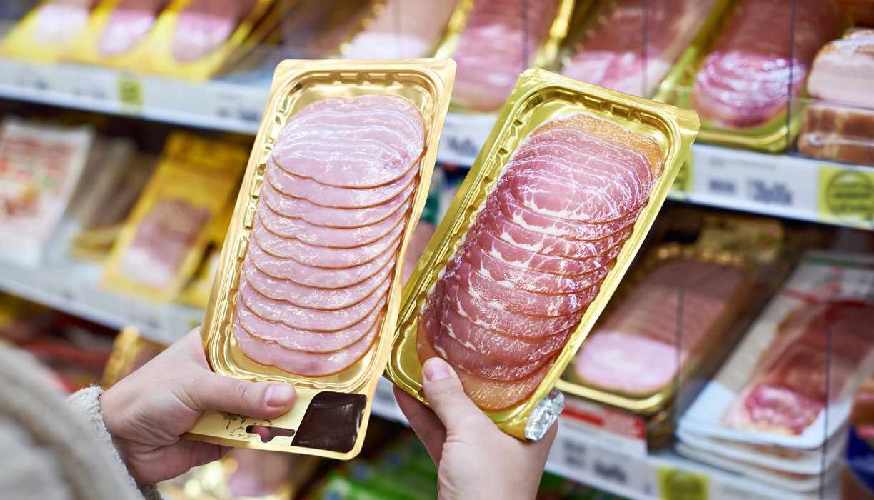 Frau, hält zwei Wurstpackungen in der Hand.