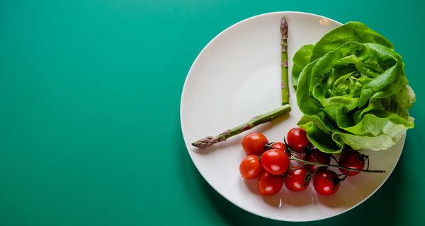 Teller mit Salat, Tomaten und Spargel: Die beiden Spargel-Stängel deuten eine Uhrzeit an.