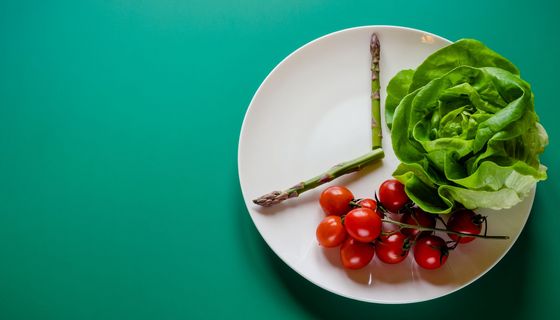 Teller mit Salat, Tomaten und Spargel: Die beiden Spargel-Stängel deuten eine Uhrzeit an.