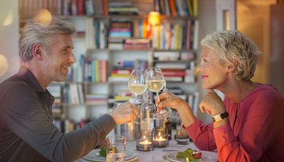 Frau und Mann stoßen an bei einem gemütlichen Abendessen.