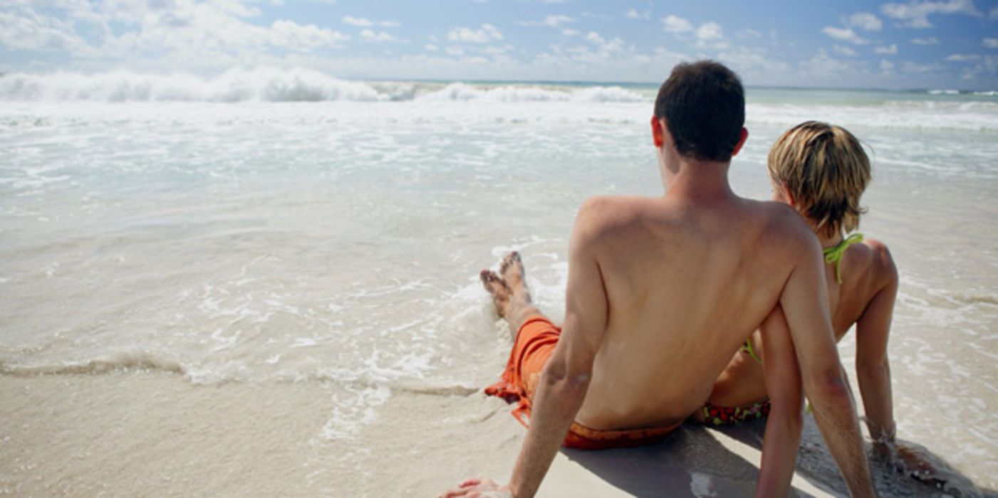 Junges Paar sitzt am Strand.