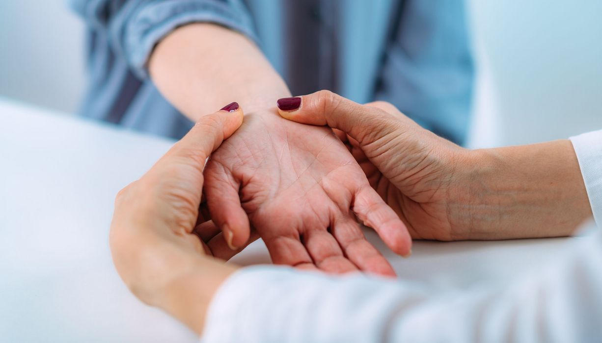 Arzt, behandelt das Handgelenk einer Patientin.