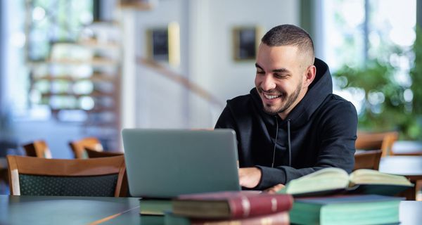 Junger Mann, sitzt am Laptop.