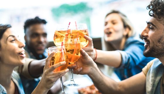 Junge Leute stoßen mit einem alkoholischen Getränk an.