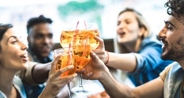 Junge Leute stoßen mit einem alkoholischen Getränk an.