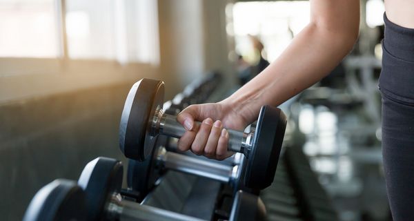 Frau, nimmt eine Hantel im Fitnessstudio.