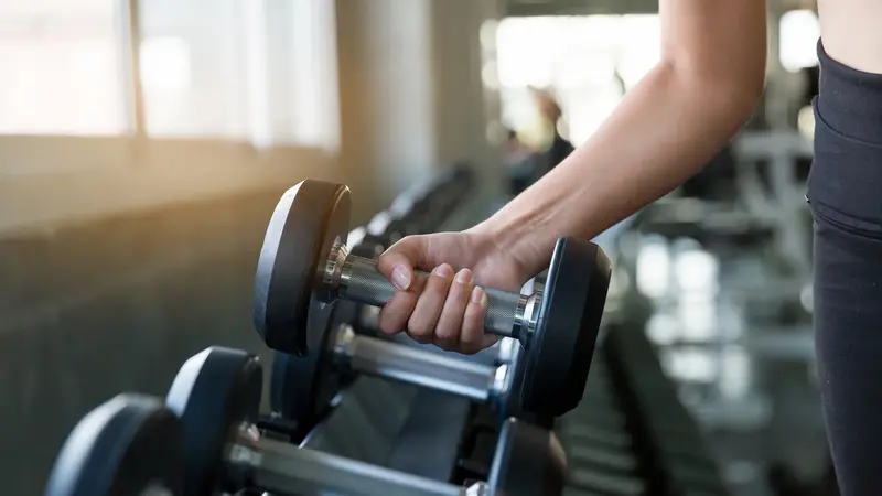 Frau, nimmt eine Hantel im Fitnessstudio.