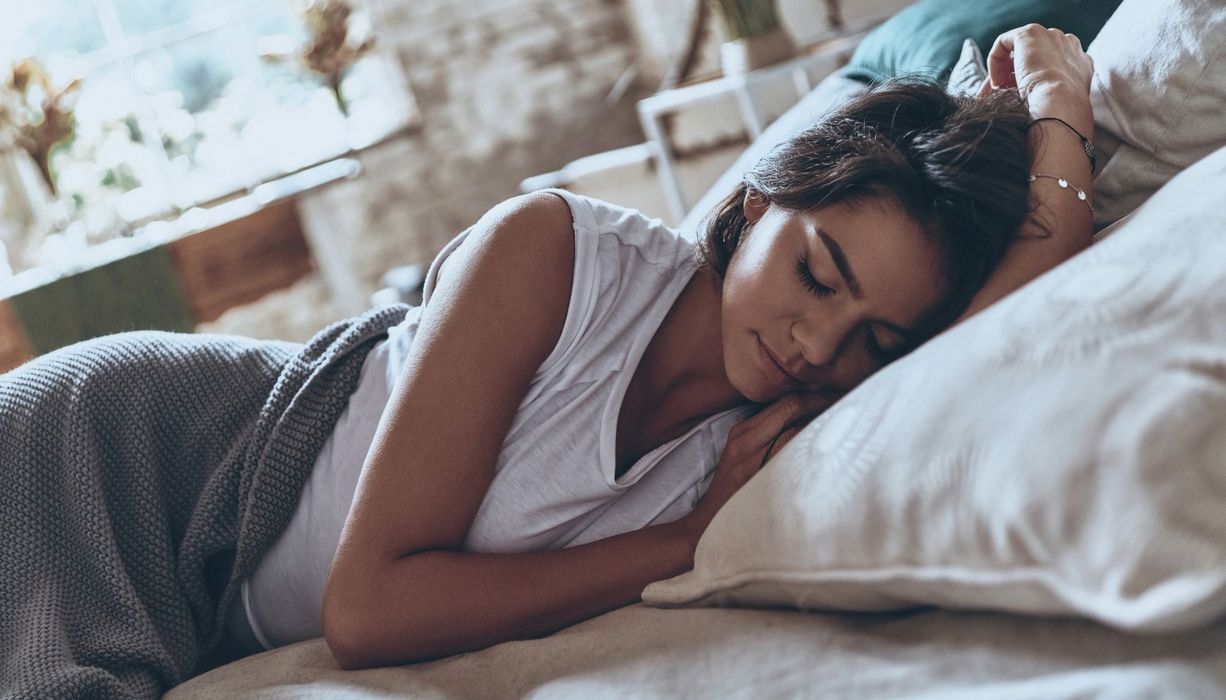 Junge Frau liegt im Bett und schläft.