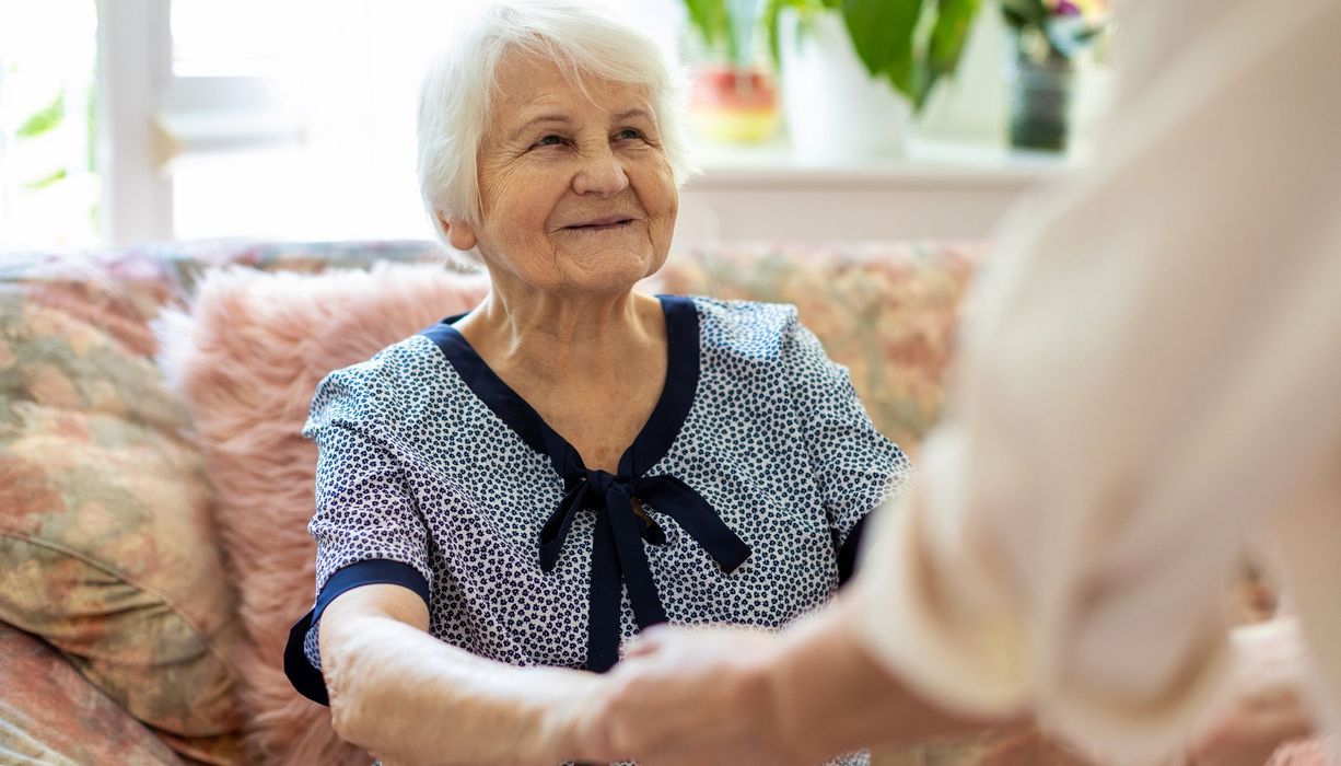 Frau, hält die Hände einer Seniorin.