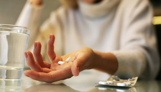 Junge Frau, hält Schmerzmittel in der Hand.