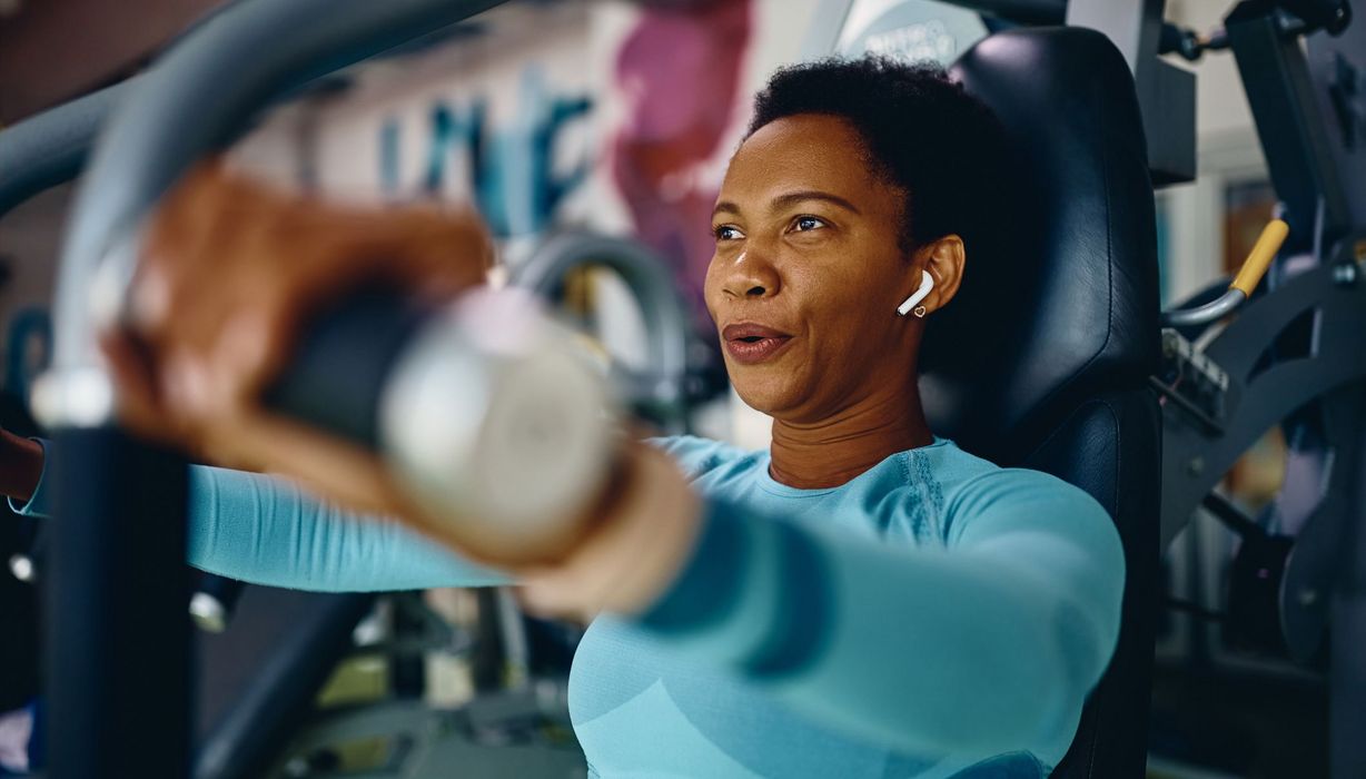 Frau im Fitnessstudio, trainiert an einem Gerät.