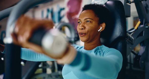 Frau im Fitnessstudio, trainiert an einem Gerät.