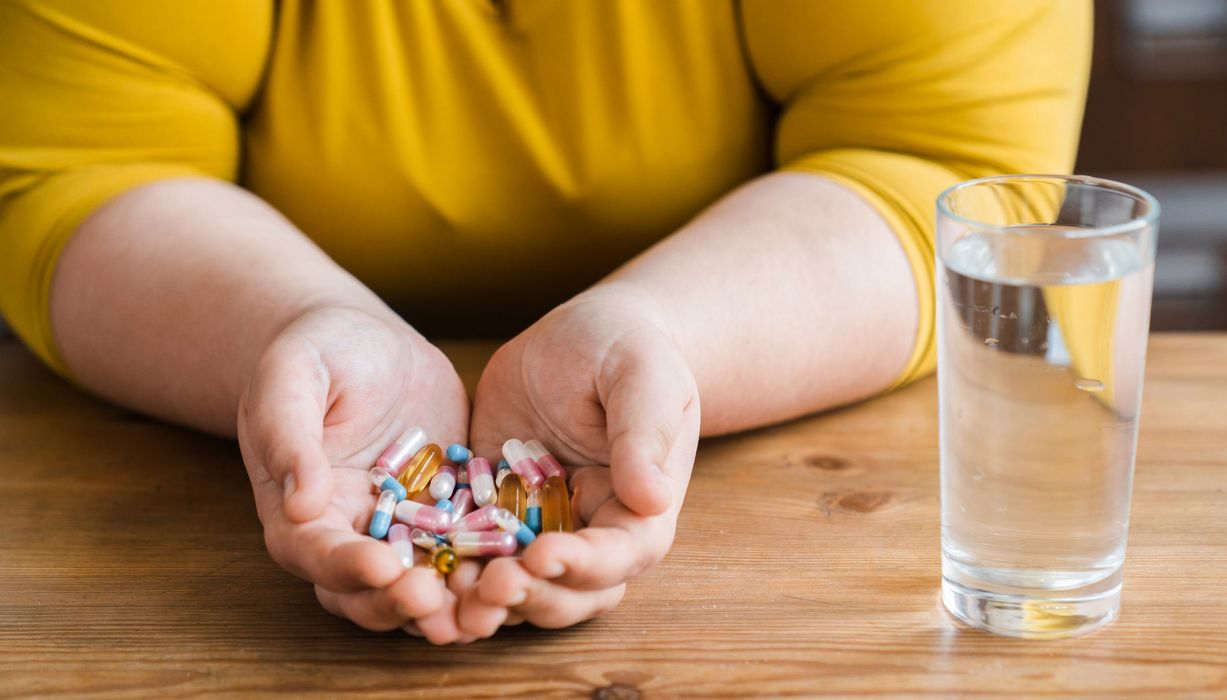 Frau, übergewichtig, hält Tabletten in ihren Händen.